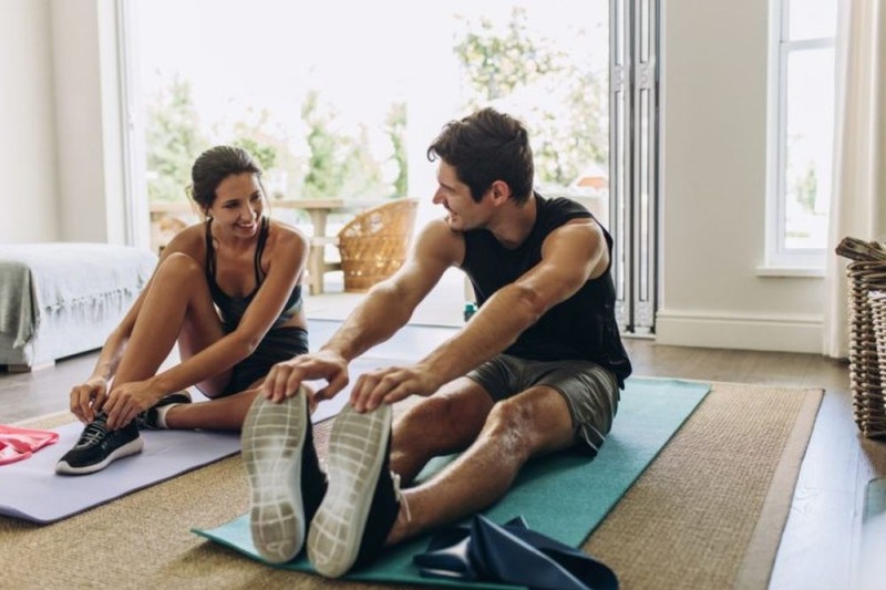 a man and woman sitting on the floor stretching