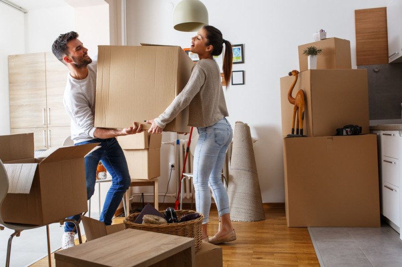 a man and a woman in a room with boxes and a lamp