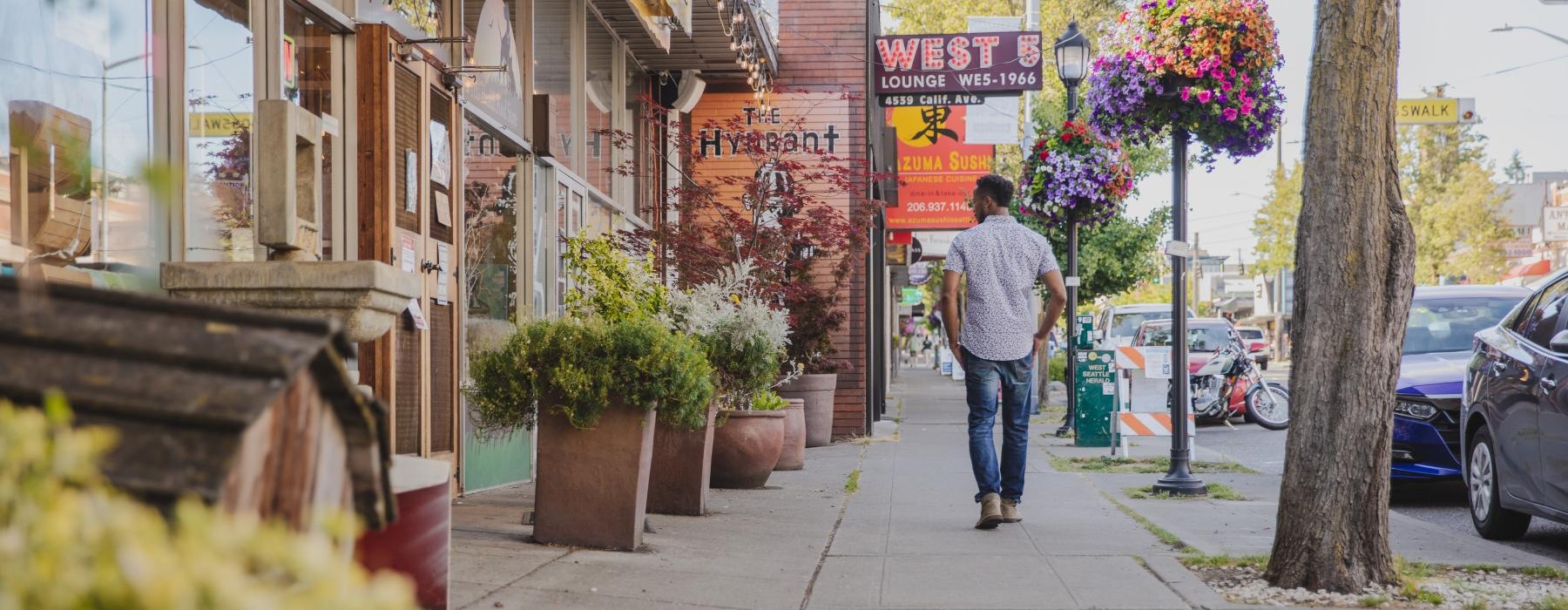 a person walking down a sidewalk along retailers