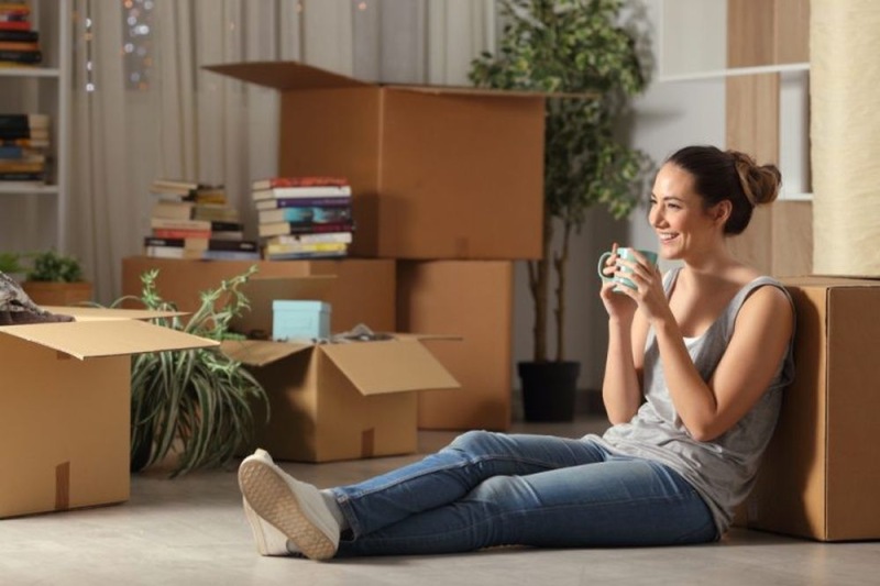 a woman sitting on the floor near moving boxes