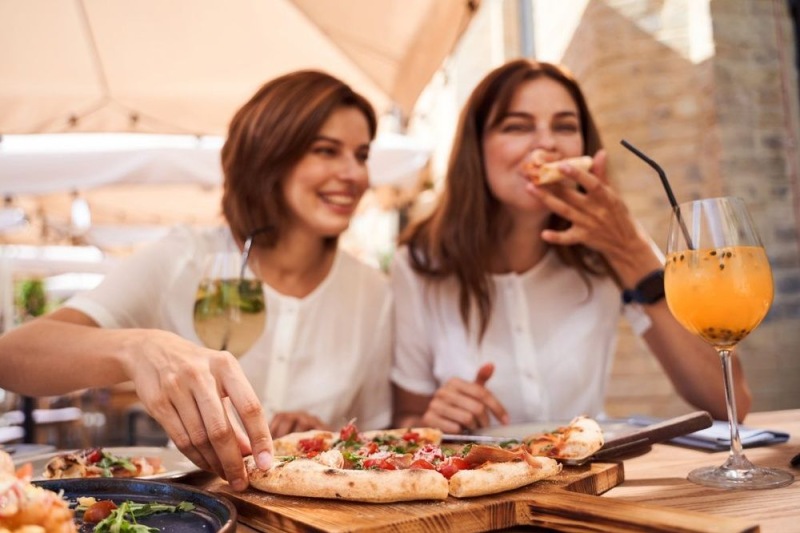 a couple of women eating pizza