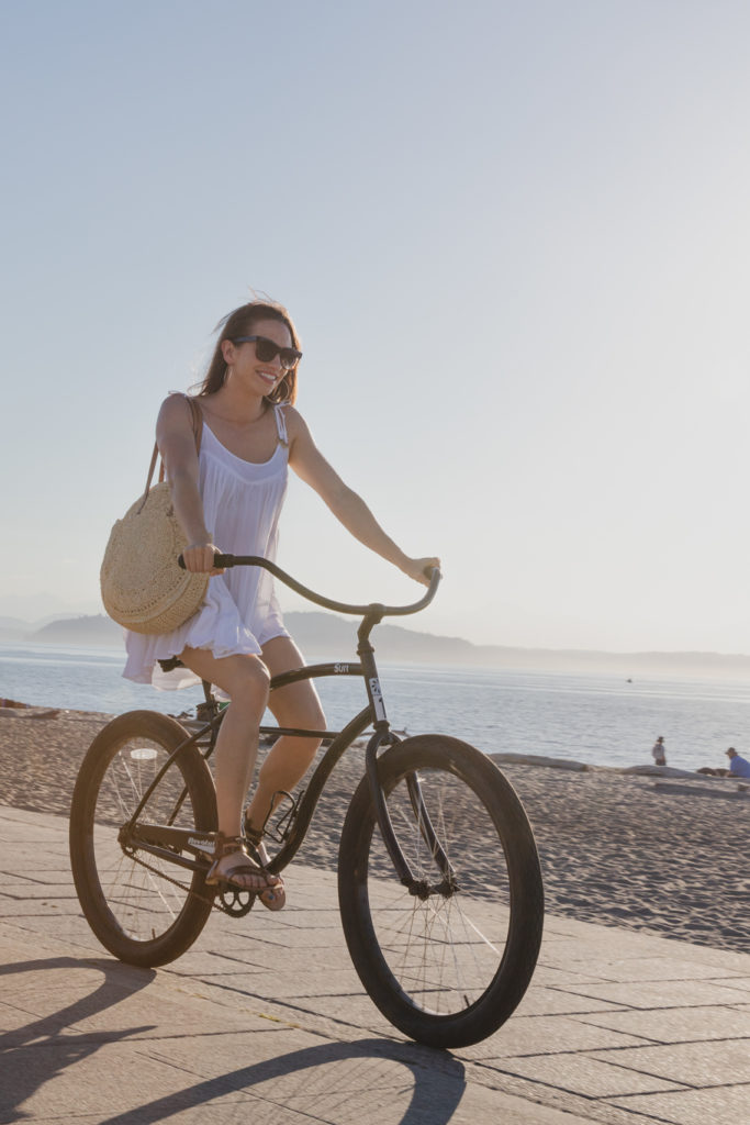 Marsis Seattle young lady on a cruiser bike riding by a beach