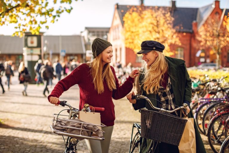 female friends pushing their bicycles in the city